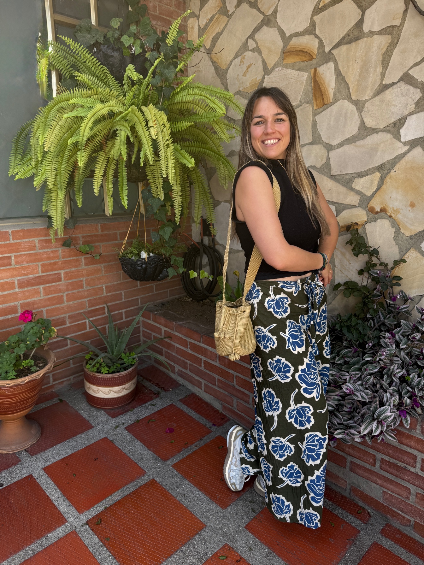 A woman holding a colorful handwoven Wayuu mochila against a terracotta wall in Colombia